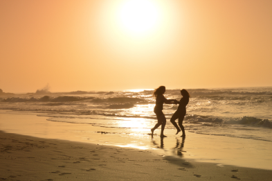 Zwei Frauen drehen sich am Meer bei Sonnenuntergang 
