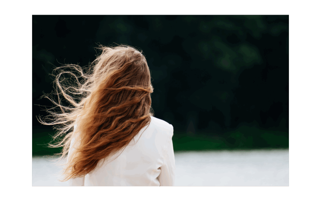 Frau mit wehenden Haaren blickt in die Ferne