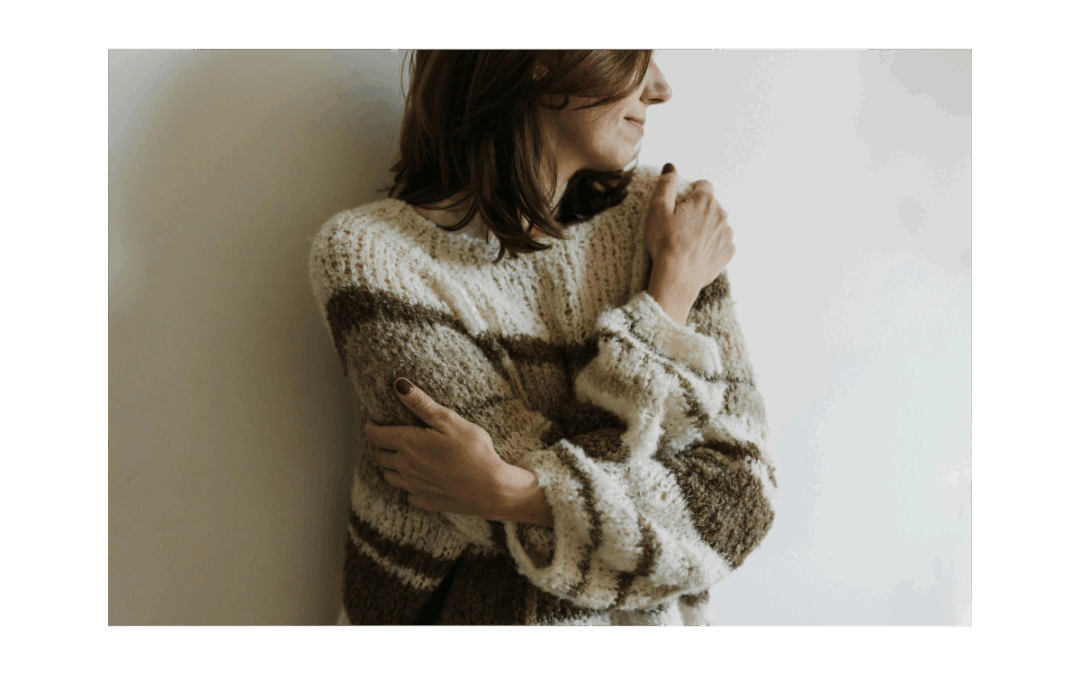 Eine Frau umarmt sich selbst und lächelt leicht dabei